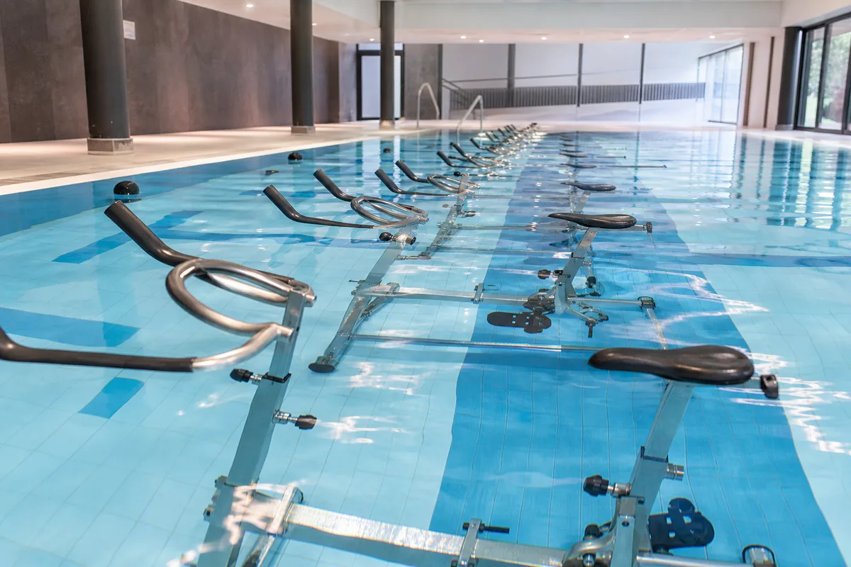 Bassin de piscine intérieure équipé de vélos d’aquabike alignés sous l’eau claire, ambiance lumineuse